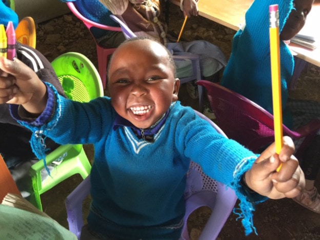 Little boy in nursery school (baby class) receives school supplies.  He is as happy as the sun is hot!
